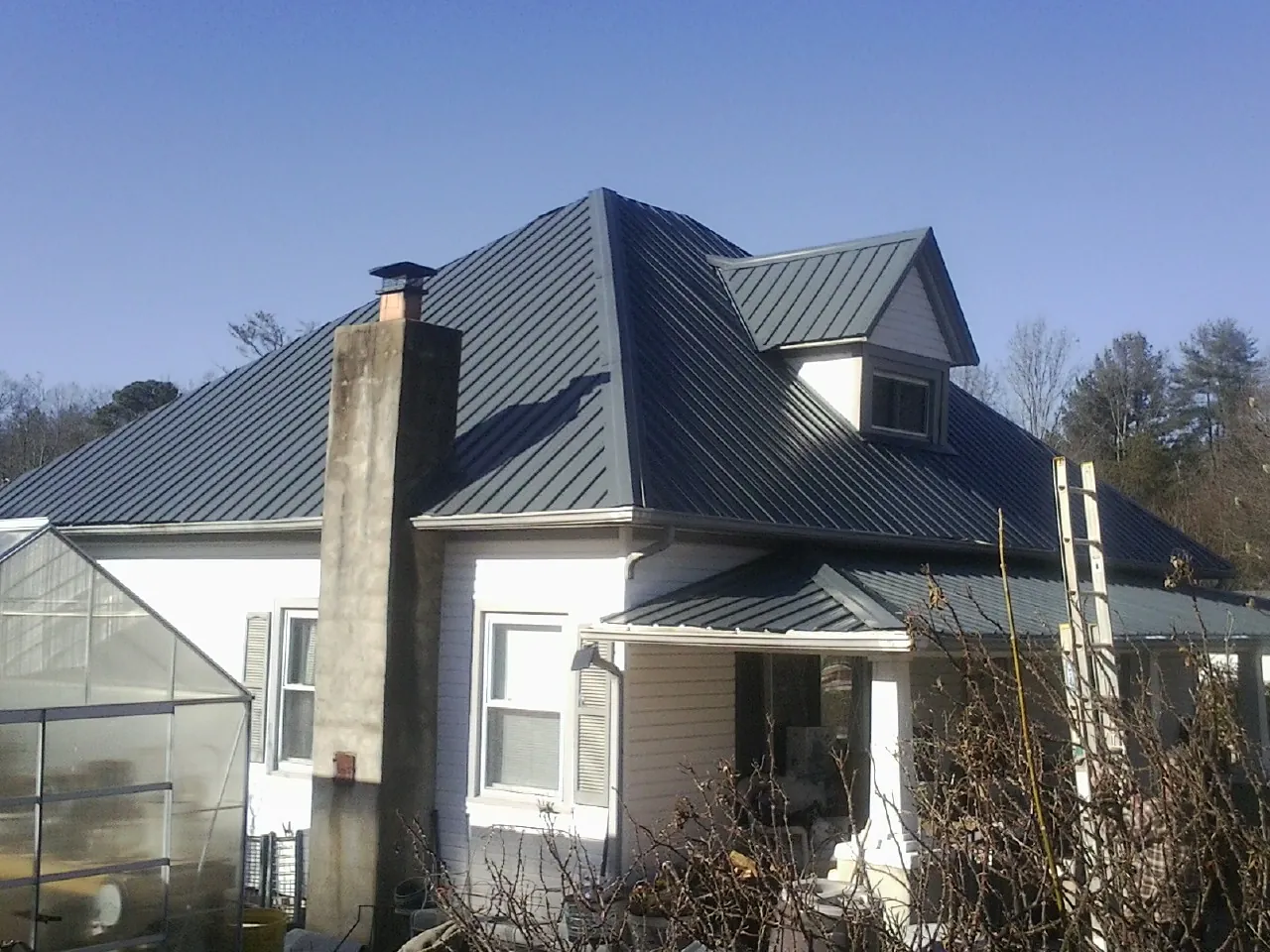 Dark blue standing seam metal roof on a white farmhouse with dormer — Slate & Tile Roof Repair by Roofing Brothers in Salt Lick