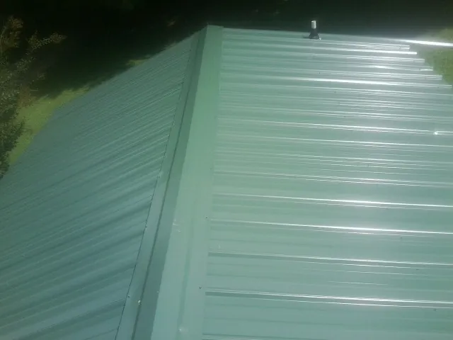 New green metal panels meeting at the ridge of a roof — Flat Roof Repair work by our crew in Salt Lick