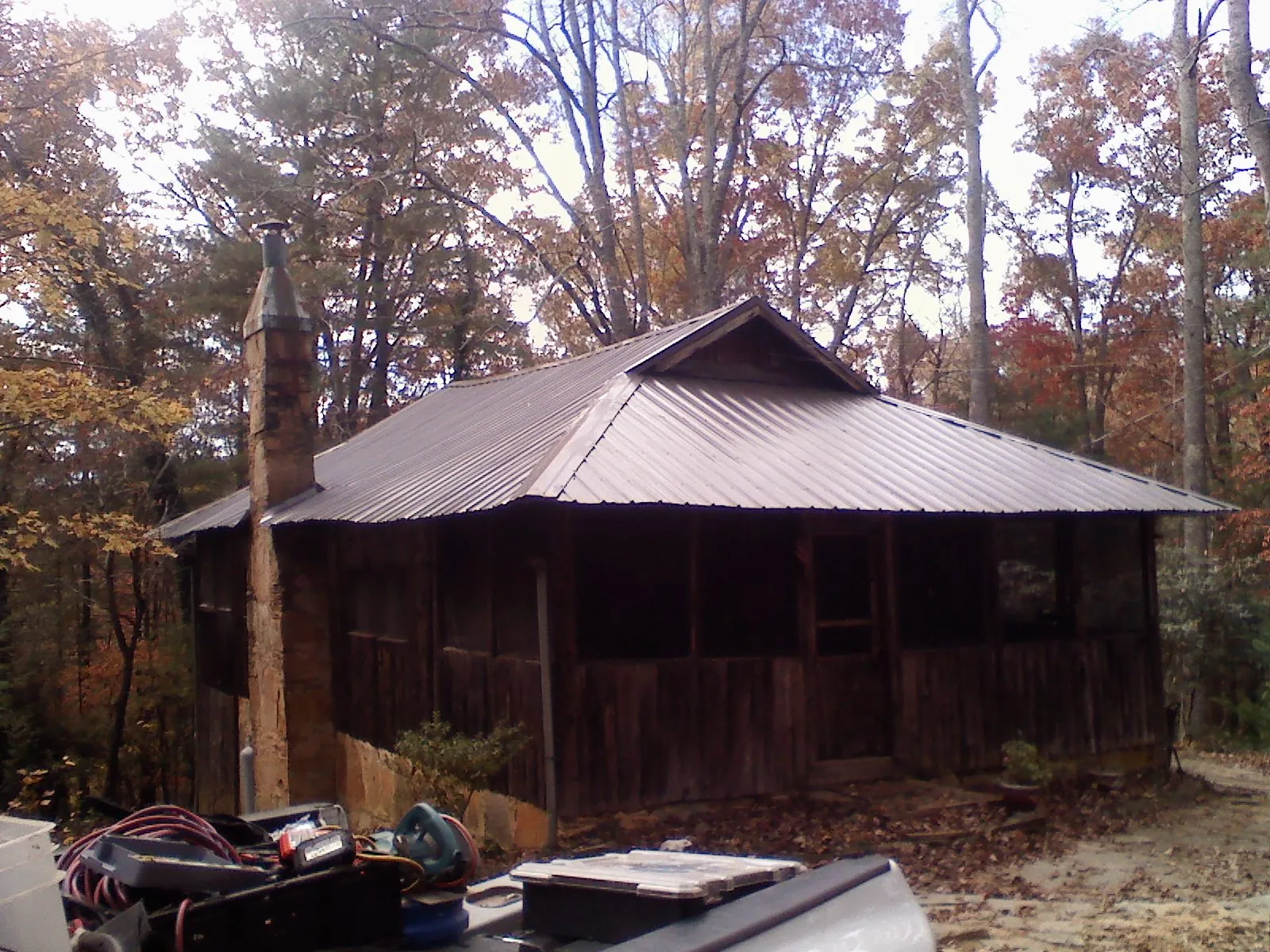 Brown metal hip roof on an old cabin with a stone chimney in Salt Lick