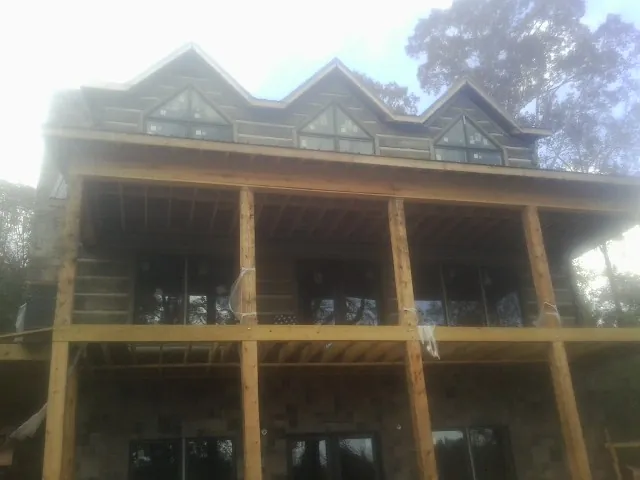 Dormers and porch framing on a large log home under construction — Roof Coating work by our crew in Salt Lick