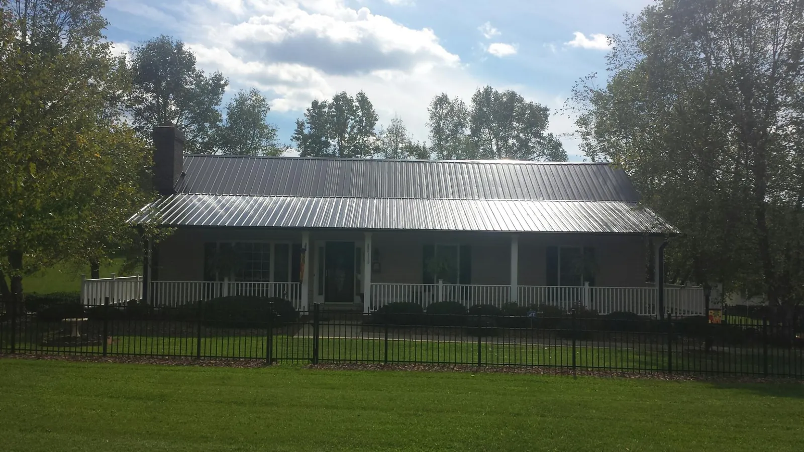 Gray metal roof on a brick ranch with a full width front porch — Gutter Guard Installation work by our crew in Salt Lick