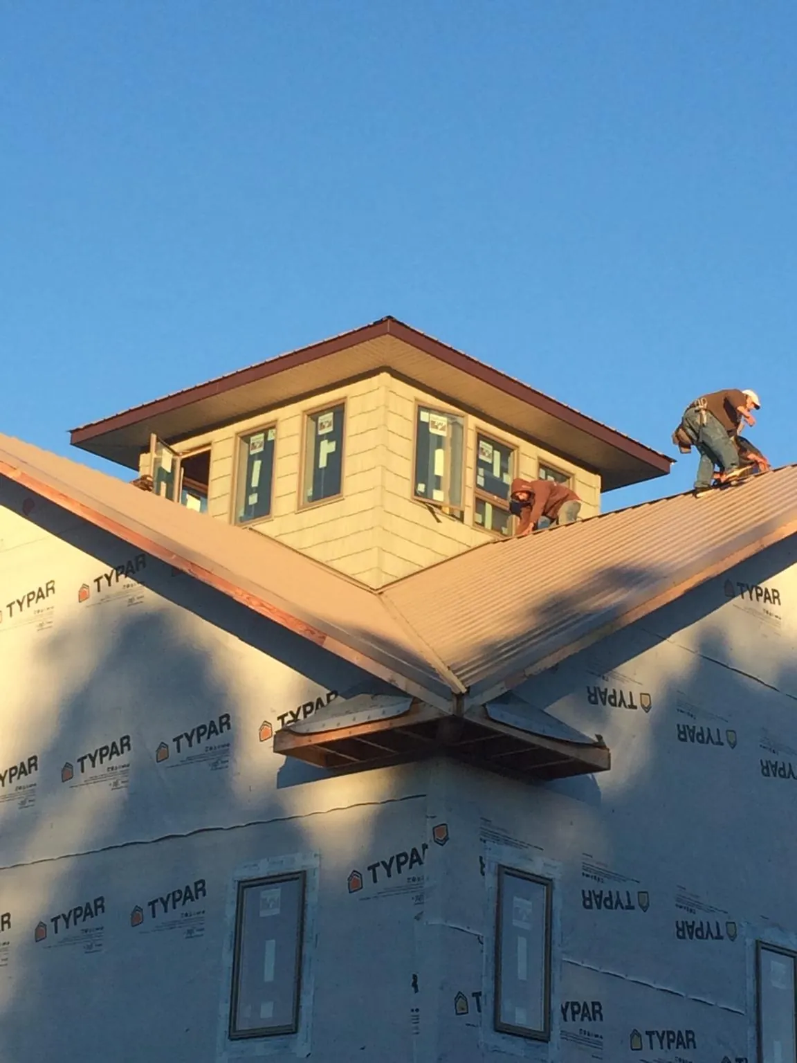 Roofers working around a rooftop cupola on a new metal roof at sunset — Roof Waterproofing in Salt Lick by Roofing Brothers
